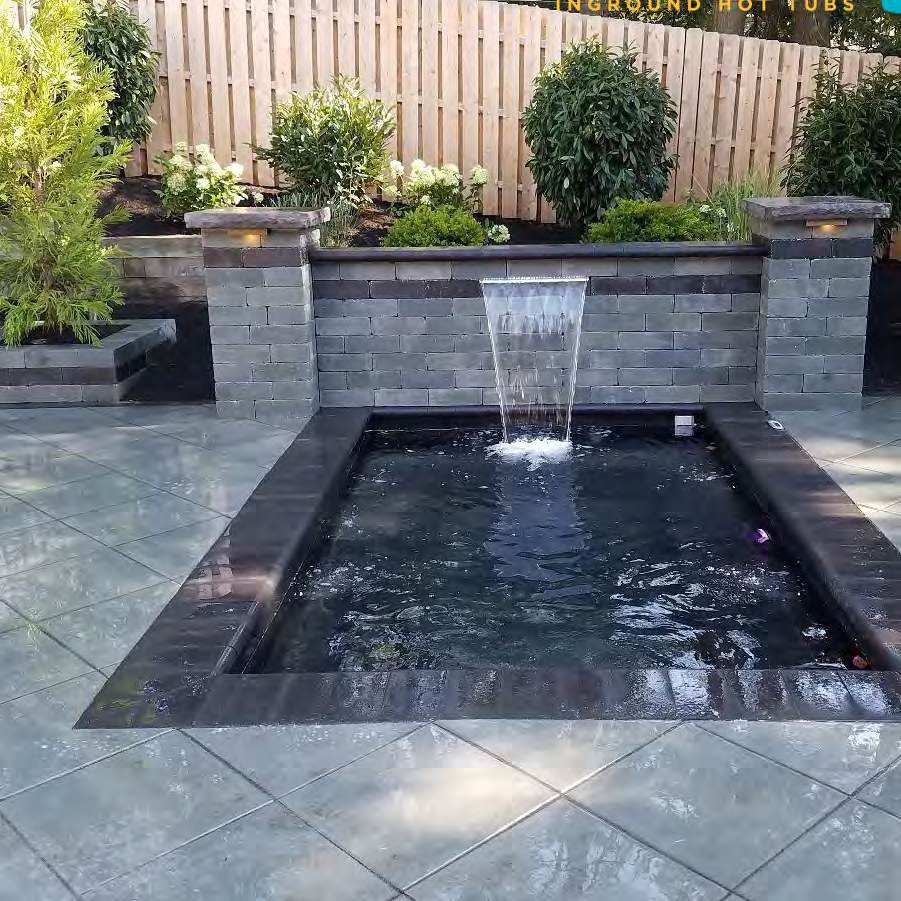 Dark reflecting pool with a sheer descent water feature and paver surround